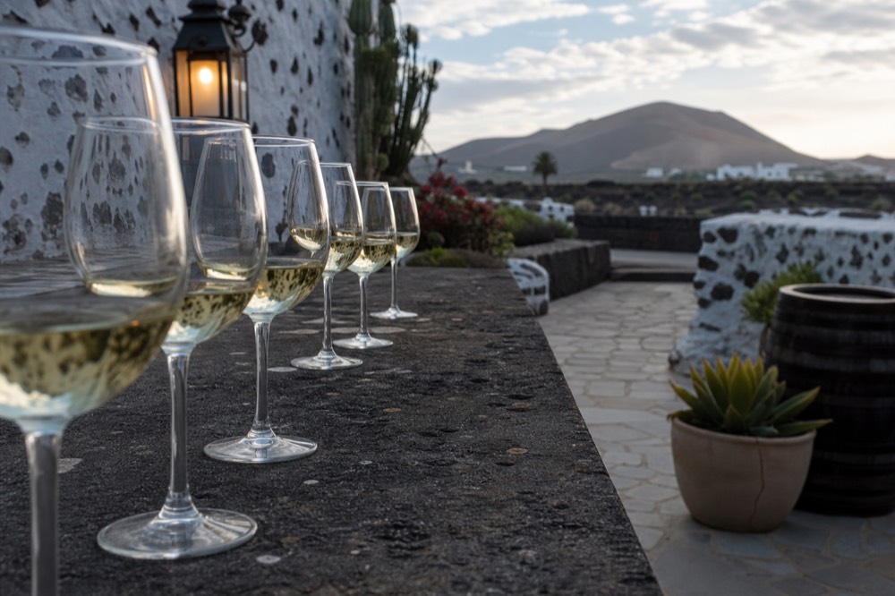 A row of white wine glasses on a dark stone tasting counter