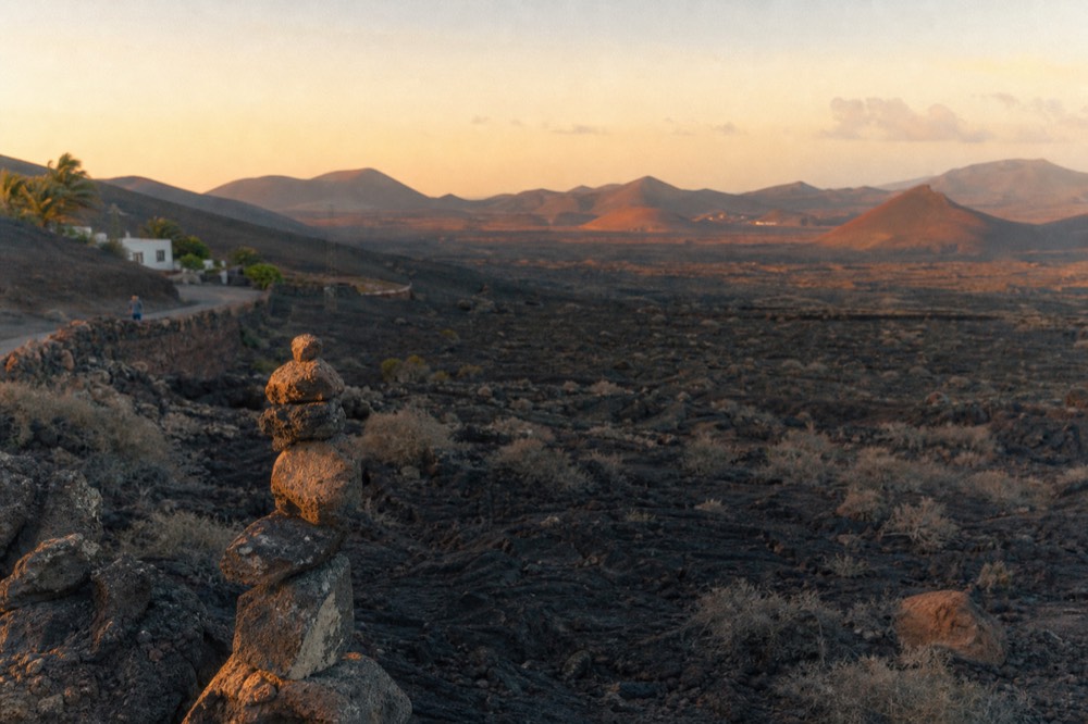Cracked black lava fields of Timanfaya with reddish volcanic cones in the distance