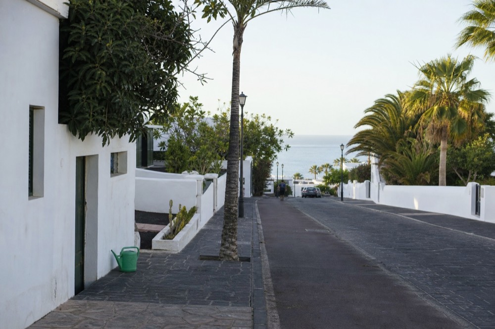 A quiet resort street in Puerto del Carmen with low white buildings and palm trees