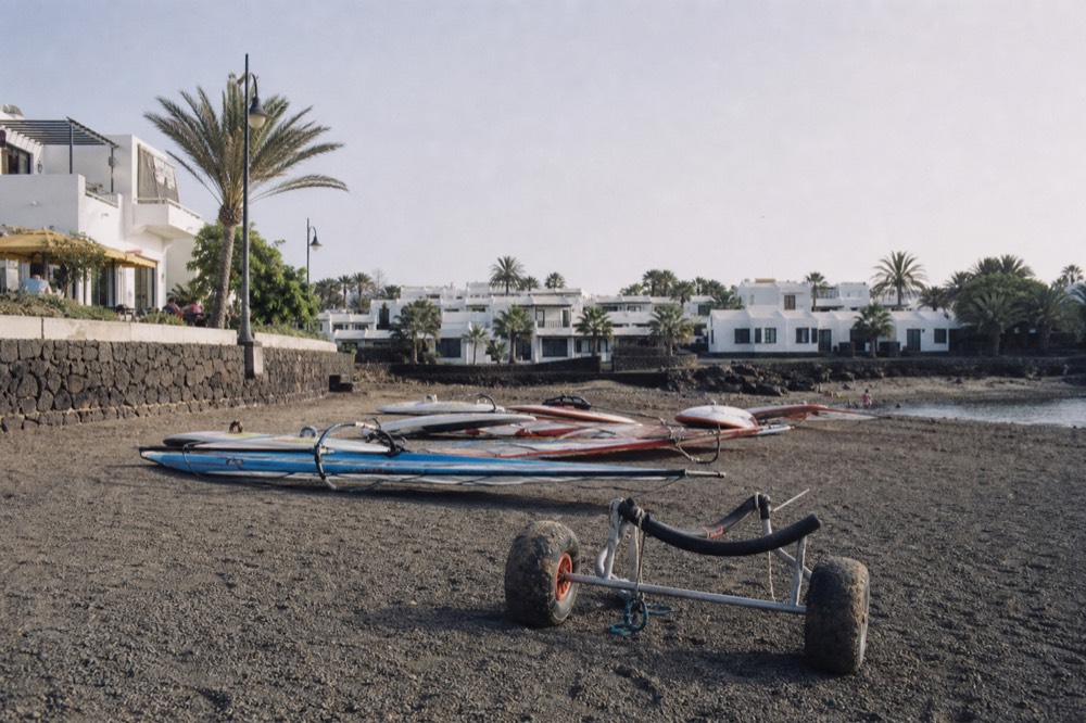A windsurfing beach at Costa Teguise with low white resort buildings behind