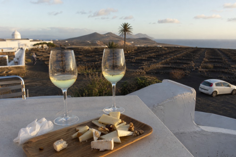 Cheese board and glasses of wine on a terrace overlooking volcanic countryside
