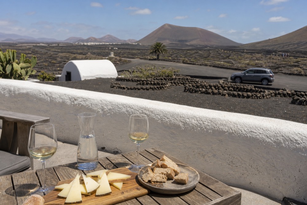 A table with Canarian goat cheese, bread and glasses of white wine on a winery terrace