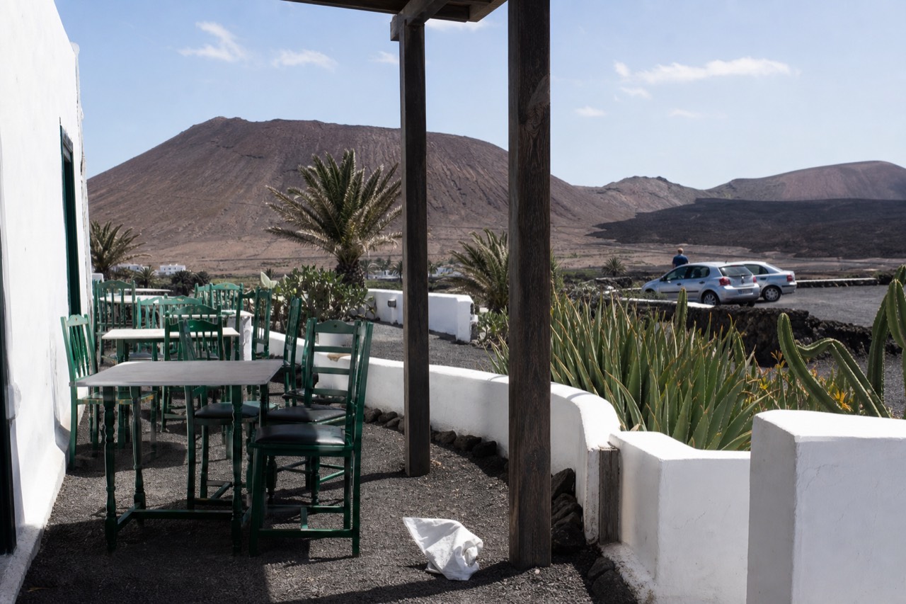 A whitewashed Canarian village restaurant terrace under a volcanic ridge