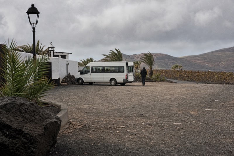 Minibus waiting outside a Canary Island winery entrance in dark lapilli soil