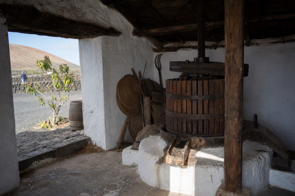 Old wine press and dark wooden beams inside a traditional Lanzarote winery building