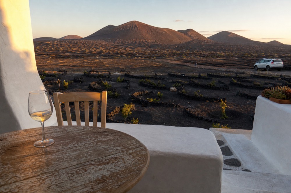 Sunset light over volcanic cones and ash vineyards seen from a winery terrace