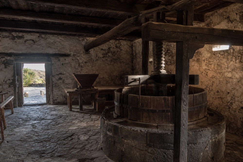 Old stone wine press and wooden beams inside a historic Canarian winery