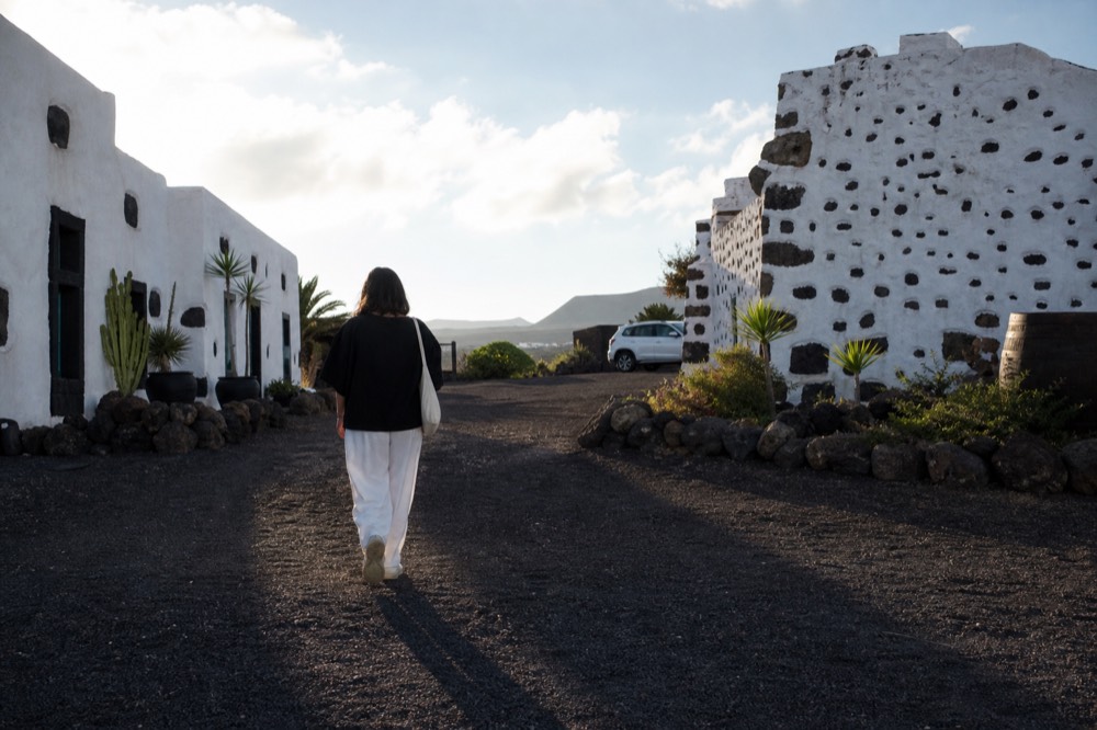 Visitor walking a path between old stone buildings at a Lanzarote winery