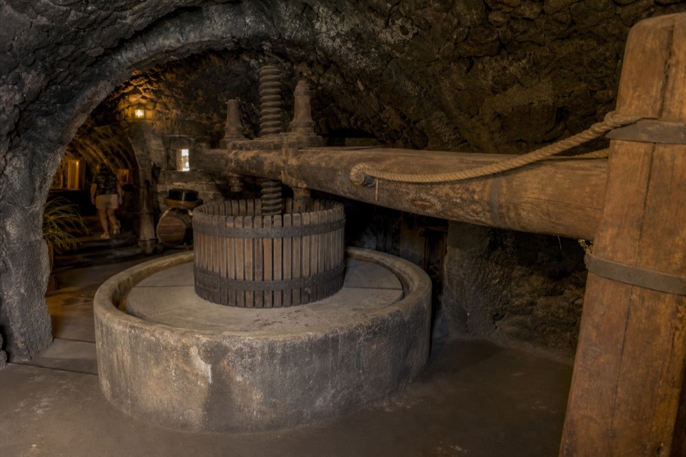 Ancient wooden wine press and stone vat in a dim historic cellar