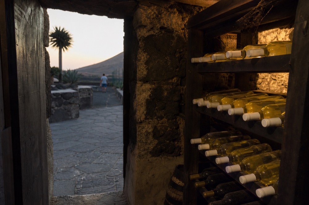 Bottles of white wine on a wooden rack in a volcanic stone cellar