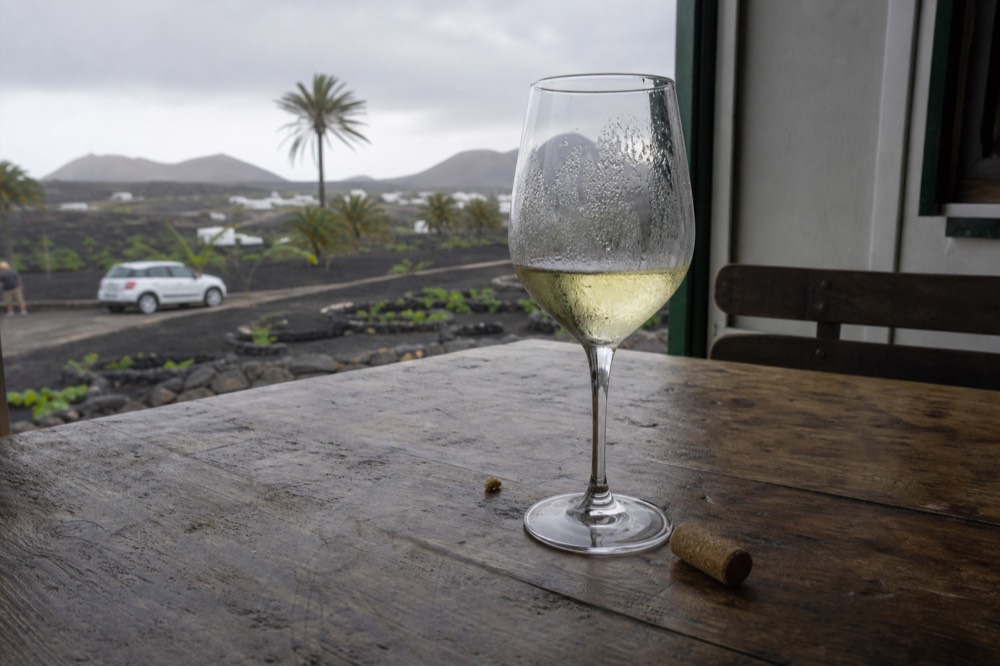 Close-up of a glass of white wine on a wooden table with vineyards behind
