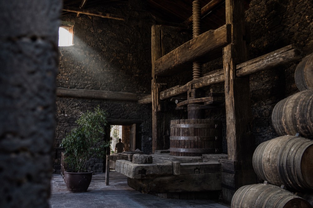 Old wine press and barrels inside a stone winery