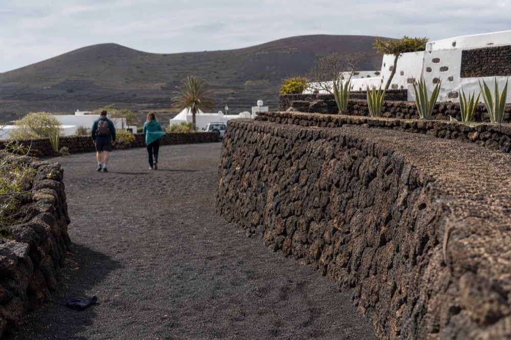 Hikers walking past a zoco in La Geria