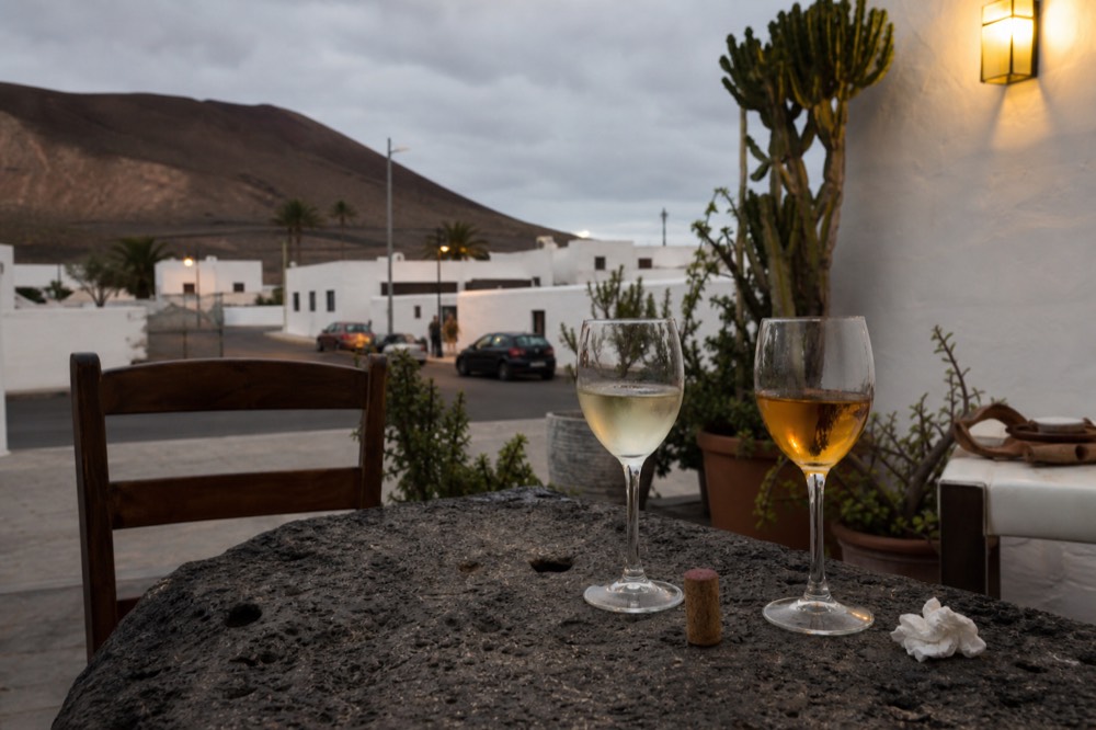 Two glasses of white wine on a volcanic stone table, one dry and one amber sweet