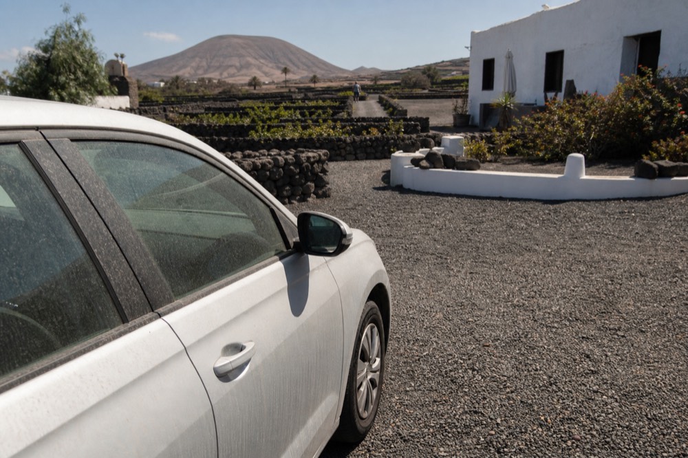 A car parked outside a white bodega building