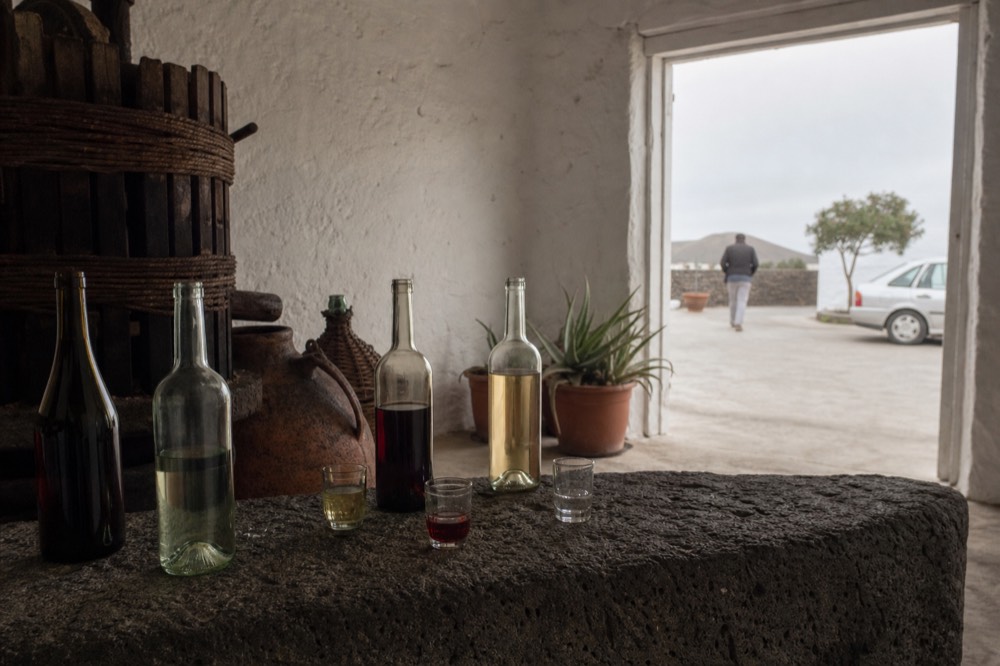 A tasting counter inside a Lanzarote bodega with open bottles and small pouring glasses
