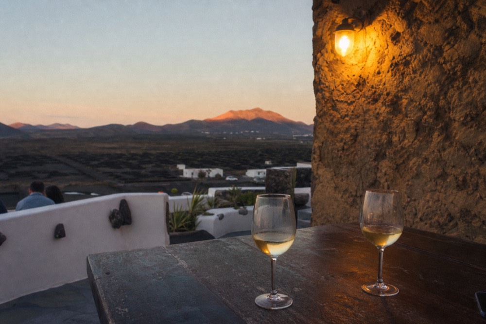 Terrace at dusk overlooking volcanic countryside with glasses of white wine