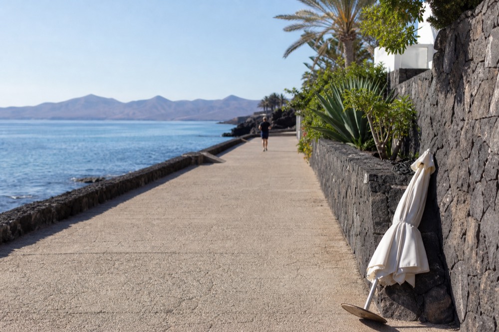 Playa Blanca promenade at morning with calm water and distant volcano shapes